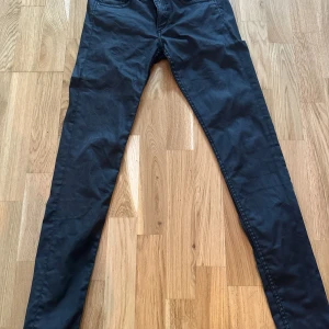 Svarta super skinny jeans från H&M - Svarta super skinny jeans från H&M med låg midja och klassisk femficksdesign. Jeansen är tillverkade i stretchigt denim-material som sitter tight och följer kroppen. Perfekt för dig som gillar en smal siluett och vill ha en modern look.