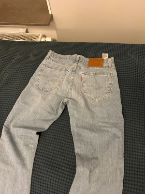Levis ljusblå jeans straight fit - Ljusblå Levis jeans med klassisk femficksdesign och raka ben. Jeansen har en snygg vintage-wash och är tillverkade i mjukt denim med Levis ikoniska läderpatch bak i midjan. Passar dig som gillar en clean och tidlös look.