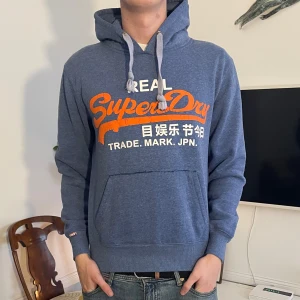 Blå Superdry hoodie  - Skön superdry hoodie, storlek M men sitter mer som S. Modellen är 187. Hör av dig vid minsta fundering🤗