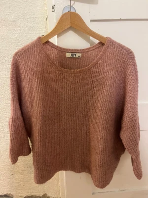Rosa stickad tröja från JDY - Mysig stickad tröja i en ljus rosa ton från JDY. Tröjan har rund halsringning och trekvarts ärmar med en loose passform.