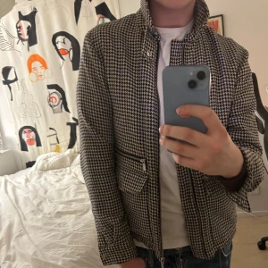 Hundtandsmönstrat jacka från Scotch and Soda - Snygg hundtandsmönstrad jacka från Scotch & Soda AMS Blauw i svart, vit och blå. Jackan har dragkedja framtill, två fickor med dragkedja och klassisk krage. Mönstret är hundtandsrutig.  Notera att ena knappen på fickorna är trasig. Jackan är gjord för män men enligt mig hade den passat tjejer väldigt snyggt också! Nypris drygt 2000kr
