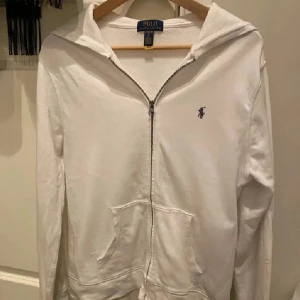 Vit Ralph Lauren zip hoodie - Vit hoodie från Polo Ralph Lauren i storlek junior XL som motsvarar XS. Nypris: ca 1100kr. Klassisk design med dragkedja, huva och två fickor framtill. Liten broderad blå logga på bröstet. Använd max 5 ggr och i ett gott skick. Lådan kommer med. Hör gärna av dig vid frågor elr liknande🙌