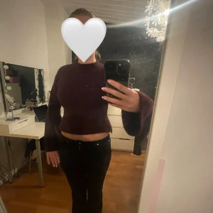 Vinröd croppad stickad tröja - Säljer en vinröd  stickad tröja med långärmade och lite vidare ärmar. Tröjan är lite tajtare i midjan för att sedan gå ut lite. 