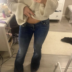 Blå bootcut jeans f - Snygga blå jeans med bootcut passform och låg midja. Jeansen har klassisk femficksdesign, dragkedja och knapp framtill. Materialet är slitstarkt denim och färgen är mörkblå med lätt tvättade detaljer. Perfekt för dig som gillar retrovibe och cool siluett.