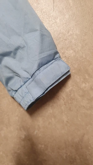 Vindjacka - Säljer en svart och ljusblå vindjacka från Crivit. Jackan har dragkedja framtill, meshfoder och elastiska muddar vid ärmslut. Praktiska fickor och snygga kontrastdetaljer. Perfekt för blåsiga dagar och enkel att matcha med streetwear.