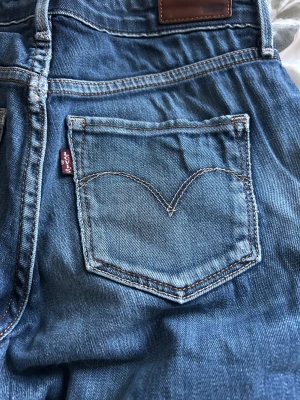 Levi's blå jeans straight fit - Säljer ett par klassiska blå Levi's jeans med rak passform och snygga slitningar. Säljer då de är för stora för mig och sitter konstigt. Storlek är 26/32
