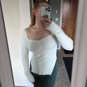 Vit ribbad topp - Säljer en vit ribbad långärmad topp med fyrkantig urringning och figurnära passform. Materialet är mjukt och stretchigt, perfekt för dig som gillar en clean och stilren look. Snygga detaljer med stickad struktur framtill. Aldrig använd 💜