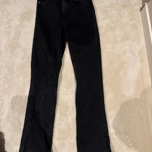 Svarta jeans med slits från 157 - Svarta jeans från 157 i storlek S. Modellen har raka ben med snygga slitsar nertill för en trendig look. Klassisk femficksdesign, dragkedja och knapp framtill. Perfekta till sneakers eller boots och gjorda i mjukt jeanstyg.