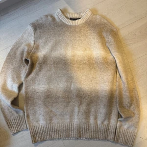 Beige stickad tröja från 157 - Mysig beige stickad tröja från 157 med rund halsringning och ribbade muddar vid ärmslut och nederkant. Perfekt för lager på lager och chill dagar. Enkel och stilren design som funkar till det mesta. Sitter som M, använd 1 gång.