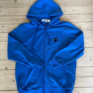 Blå hoodie Comme des Garçons Play - Blå hoodie från Comme des Garçons Play, storlek M men passar nog Large eftersom den är lite stor i storleken! Hoodien är ej äkta!!