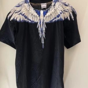 Svart t-shirt med blått och vitt fjädertryck - Storlek S men passar M