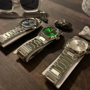 Stilren TPW klocka med metallarmband - Säljer en snygg egen designad klocka med robust metallarmband och klassisk rund boett. Finns med urtavla i silver, grön eller blå. Klockan har dag- och datumvisning och en stilren design som passar dig som gillar cleana accessoarer.