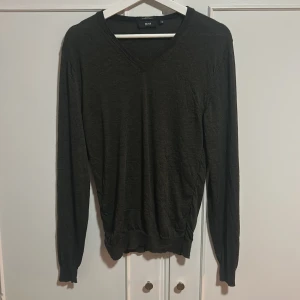 Svart merinoullströja från Hugo Boss - Snygg svart tröja från Hugo Boss i extrafin merinoull. Slim fit-modell med v-ringning och långa ärmar. Perfekt för dig som gillar stilrena och klassiska plagg med en modern passform.