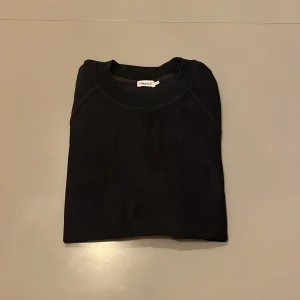 Svart sweatshirt från Filippa K - En stilren svart sweatshirt från Filippa K med rund halsringning. Tröjan har en klassisk passform och är tillverkad i mjuk bomull, perfekt för en clean och enkel look. Passar dig som gillar minimalistisk stil.