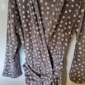 Grå morgonrock med stjärnor från Hemtex - Supermjuk grå morgonrock från Hemtex vita stjärnor över hela. Morgonrocken har huva, långa ärmar och knyts med bälte i midjan. Perfekt för att chilla hemma eller mysa runt i. Snygg och cozy vibe!