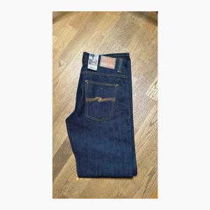 Mörkblå jeans från Nudie Jeans - Sprillans nya Average Joe dry dirt organic otvättade. Eftersom dom är otvättade och helt oanvända är dom perfekt för dig som skapa dina egna jeans med åren. Tveka ej på att höra av dig om du har några frågor gällande jeansen!