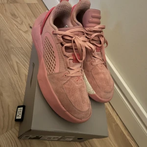 Rosa sneakers från Li-Ning - Säljer ett par snygga rosa Li-Ning sneakers med meshpaneler och mockadetaljer. Skorna har snörning, platt sula och rund tå. Färgen är ljusrosa med inslag av mörkare rosa och coola mönster på hälen. Perfekta för dig som gillar unik design och sportig vibe.