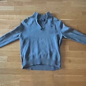 Grå stickad tröja från Ralph Lauren - Snygg grå stickad tröja från Ralph Lauren med ribbad krage och muddar. Bra skick, storlek S men passar även större