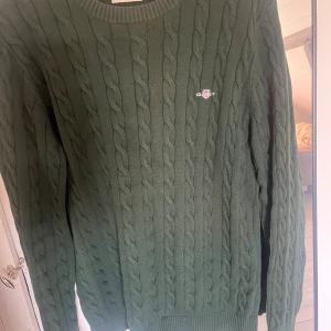 Mörk grön kabelstickad Gant tröja  - En mycket fin och behaglig kabelstickad tröja från Gant, fungerar fint till stort sätt alla årstider. 100% bomull. Nypris: 1600kr 