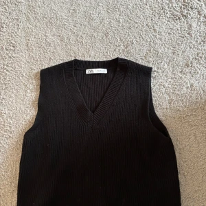 Svart stickad väst från Zara - Svart stickad väst från Zara med v-ringad halsringning. Klassisk och enkel design som är lätt att styla över en skjorta eller t-shirt. Mjuk och skön känsla tack vare det stickade materialet.