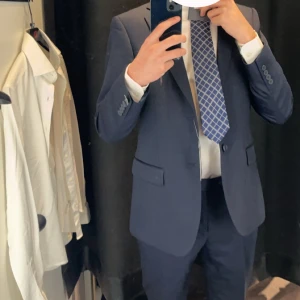 Mörkblå kostym Dressmann slim fit 46 - Mörkblå kostym, säljer bara kavaj och byxor, jag har använt det 1 gång för cirka 1,5 år sen. Kaveln är 46 short slimfit och byxorna vet jag inte riktigt, men jag är ca 175 väger 65 kg och byxorna passar när man står upp men åker upp lite mycket när man sätter sig, annars är den väldigt bra i passform och allt annat. Nypris för kavajen ligger på ca 1800kr och byxorna ca 800kr. Går inte priset bra så kom med bud