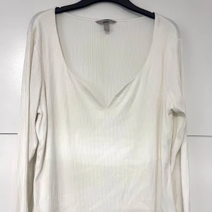 Vit ribbad långärmad topp - Snygg vit långärmad topp från med ribbad struktur och djup v-ringning. Mjuk och stretchig bomull som sitter skönt mot kroppen.