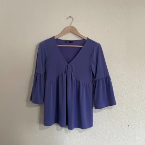 Purple blouse with trumpet arms - Measurements:  — Shirt length: 61.5 cm — Sleeve length: 41 cm