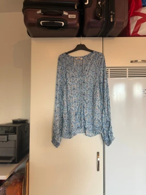 Odd molly skjorta  - Säljer en superfin skjorta i en ljusblå färg, knappar ända ner. Den har en superfint blommigt mönster. 100% viskos. Säljer en otroligt vacker Tiffany blouse i färgen deep Asphalt (brun). Den har ett superfint blommigt mönster i färgerna beige, vit och rosa. Från märket Odd Molly. Storlek 2 som enligt deras storleksguide motsvarar en M. Mycket fint skick, jag hittar inga synliga anmärkningar eller defekter. 