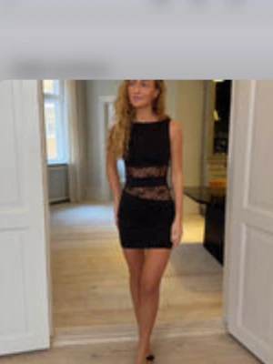 Svart kort klänning med spetsdetaljer - Säljer en svart, ärmlös kort klänning med snygga spetsinslag i midjan och över höfterna. Klänningen har en tight passform och rund halsringning, perfekt för dig som gillar en stilren men ändå edgy look. Verkar vara helt slutsåld eller borttagen då detta är den enda bild jag hittar. Från design på si med lappar kvar och endast testad 