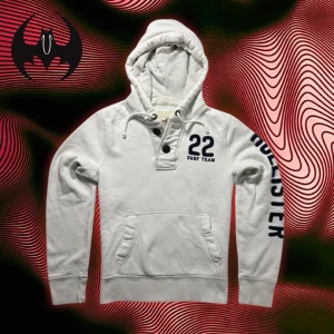 Vit hoodie Hollister  - Vit hoodie knappar från hollister med svart tryck på ärmen och bröstet | Size S | Längd: 62cm Axelbredd: 44cm Armlängd: 62cm | Modell 162, 60 kg