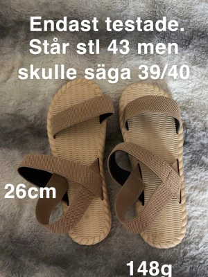 Beige sandaler med korsade remmar - Säljer ett par beige sandaler med korsade remmar och platt sula. De har en stilren design med flätad struktur i sulan och breda, elastiska remmar för skön passform. Perfekta för varma dagar och enkla att matcha med olika outfits.🌸Endast testade men för små. Står stl 43 men skulle säga 39/40. Innermått 26cm