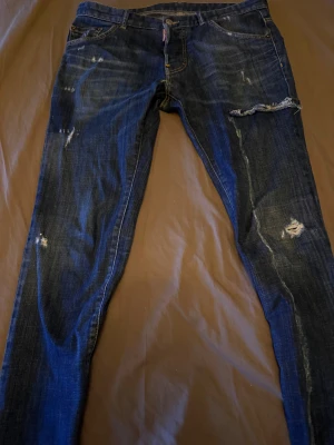 Blå jeans från Dsquared2 - Snygga blå jeans från Dsquared köpta på nk, logga vid gylfen. Materialet är 98% bomull och 2% elastan för skön stretch. Perfekt för dig som gillar en edgy streetstil. De sitter som Slim fit. 