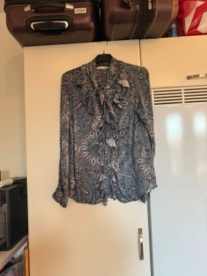 Odd molly skjorta  - Säljer en supersnygg blå skjorta med ett välsogtnvackert mönster. Knappar ända ner men volanger längst knapparna och ett band vid halsen. Från märket Odd Molly. Storlek 2 som enligt deras storleksguide motsvarar en M. Mycket fint skick, jag hittar inga synliga anmärkningar eller defekter. 