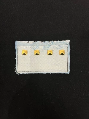 Ljusblå denim plånbok med nitar - Plånbok i ljusblå denim med fransiga kanter och fyra guldiga pyramidnitar på framsidan. Perfekt för dig som gillar en edgy och cool stil. Enkel och smidig att ha med sig i fickan eller väskan.