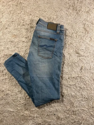 Blå jeans från Nudie Jeans, W30 L32 - Snygga blå jeans från Nudie Jeans i modellen Lean Dean färg Shoreline. Slimmad passform och nudies vågor på bakfickorna. Bra skick, men är inte sprillans nya. 