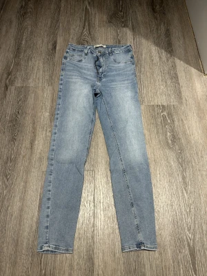 Ljusblå Molly skinny jeans strl. L - Ljusblå Molly skinny jeans från Gina Tricot med dragkedja. Jeansen har en smal passform och är tillverkade i mjukt denimtyg. Perfekta för dig som gillar en enkel och stilren look. I ena bakfickan har tråden lossnat, annars mycket bra skick, inte mycket använda.