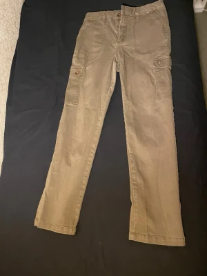 Khakigröna cargobyxor från H&M - cargobyxor från H&M med cargofickor på sidorna.Tillverkade i bomull för en skön känsla och avslappnad look. Storlek Eu 30 /uk 10 /165cm