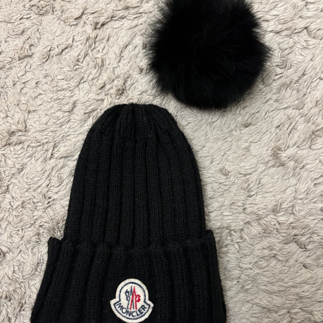 Svart stickad mössa med pälsboll