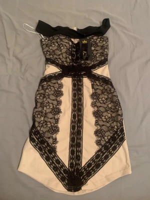 Coquette goth klänning!! - Spetsklänning i beige och svart färg, HELT NY MED ETIKETT KVAR (nwt) En så fin miniklänning med en lyxig och figurnära passform. Perfekt för fest eller utekvällar! Off shoulder :)  ORGINALPRIS: 985kr Mitt pris (nwt): 450kr (passa på att fynda!!)