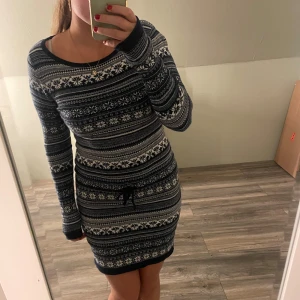 Mönstrad stickad klänning från L.O.G.G. - Mysig stickad klänning från L.O.G.G. i marinblått och vitt med klassiskt vintermönster. Modellen är kort, har lång ärm, rund halsringning och knyt i midjan. Perfekt för kalla dagar när du vill vara både varm och snygg.