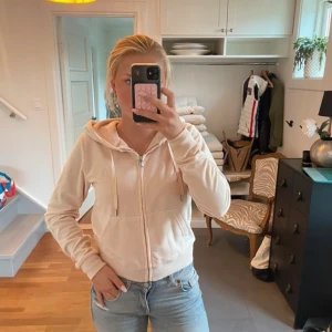 Ljus rosa  hoodie från Juicy Couture - Säljer en beige hoodie från Juicy Couture i storlek M. Tröjan har dragkedja framtill, huva med snörning och två fickor. Mjuk och skön i ett fleeceliknande material, perfekt för chill dagar. Klassisk och enkel design med ribbade muddar.
