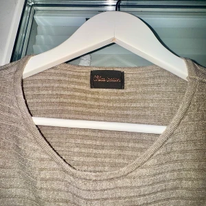 Beige ribbad tröja S/M - Beige ribbad tröja från Chica London med rund halsringning och långa ärmar. Tröjan har en loose passform och är tillverkad i en mjuk blandning av viskos och polyamid. Perfekt för lager-på-lager och inför hösten.