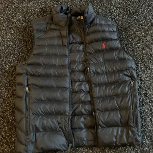 Ralph lauren väst  - Västen är använd fåtal gånger och är i gott skick utan några synliga defekter. Storleken är M och passar mig som är 185 perfekt. Hör gärna av dig vid frågor!