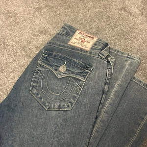 True Religion Becca Bootcut Jeans - Snygga ljusblå bootcut jeans från True Religion, modell Becca Mid Rise Bootcut. Ljusblå med urtvättat detalj jeansen, på bilden ser dom mer vita ut än i verkligheten. 🤍