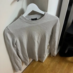 Ljusgrå stickad tröja från H&M - En stilren ljusgrå stickad tröja från H&M med rund halsringning och ribbade muddar. Perfekt för lager-på-lager och enkel att matcha med jeans eller kjol. Långärmad och i mjukt material som känns skönt mot huden.