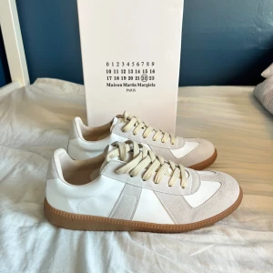 Maison Margiela gats -  Säljer ju nu ett par stilrena Maison Margiela gats som är perfekta nu till hösten för dig som vill ha en stilren look. Skorna är i mycket bra kvalitet, och kommer hålla dig länge. Skostorlek 43, insulans mått är 27 cm. 0bs lnte 0rglnal, bra kvalitet😊