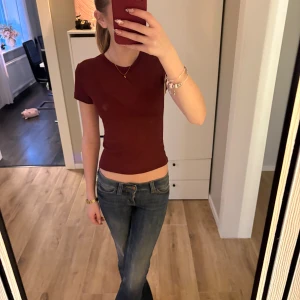 Vinröd kortärmad topp från H&M Divided - Säljer en vinröd, tight och basic topp från H&M Divided i storlek XS. T-shirten har rund halsringning och korta ärmar. Perfekt att matcha med jeans eller kjol för en enkel och snygg look.