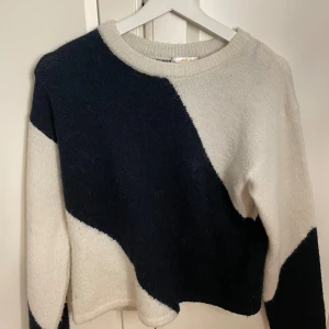 Blåvit stickad tröja Gina Tricot - Snygg stickad tröja från Gina Tricot i blå och vitt med randigt mönster. Tröjan har rund halsringning och långa ärmar, perfekt för att hålla sig varm och stilren under kyliga dagar.