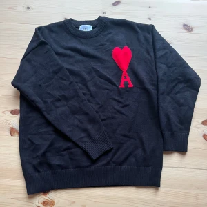 Svart stickad tröja från Ami Paris - Svart stickad tröja från Ami Paris med rund halsringning och ribbade muddar.Perfekt för dig som gillar stilrena plagg med en twist.