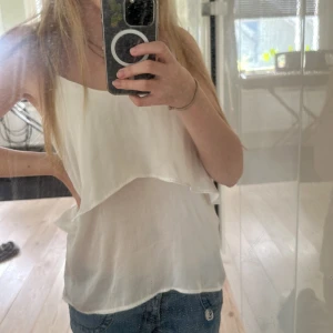 Vit volang linnetopp från Rut&Circle - Säljer en vit, luftig linnetopp från Rut&Circle i storlek 34. Toppen har tunna axelband och dubbla lager tyg som ger en snygg och flowy look. Tyget är genomskinligt så man kan ha ett linne under om man inte vill ha det. Väldigt skönt tyg.